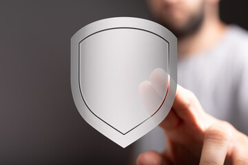 Close-up of a man's hand holding a shield, a symbol of safety, defense, security, and digital...