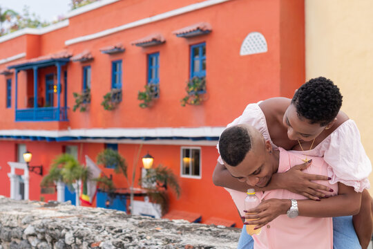 Happy couple enjoying piggyback ride in cartagena street - Powered by Adobe
