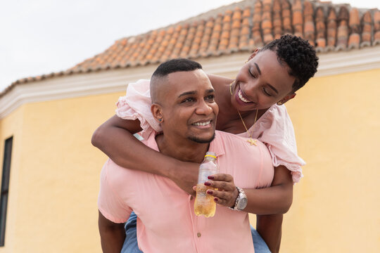 Happy black couple enjoying piggyback ride outdoors - Powered by Adobe