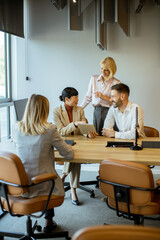 A group of four professionals engage in a meeting inside a contemporary office