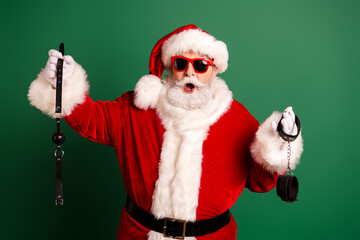 Santa in red suit with white fur trim wearing a hat and holding a leash and handcuffs for a funny festive christmas scene