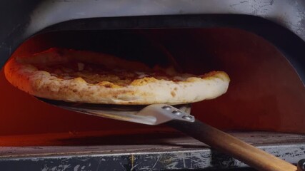 Chef Lifting Pizza with Metal Peel to Prevent Burning While Rotating It Inside Hot Oven, Concept of Artisan Pizza Baking and Culinary Precision