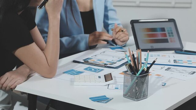 Two UX UI designers brainstorming mobile app wireframes in a modern startup office, showcasing creative teamwork, digital design