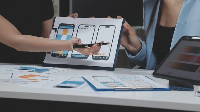 Two UX UI designers brainstorming mobile app wireframes in a modern startup office, showcasing creative teamwork, digital design