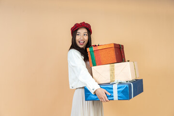Young Asian Woman with Stack of Holiday Gifts Expressing Surprise and Joy During Christmas Season Shopping Experience in Studio Perfect for Seasonal Marketing