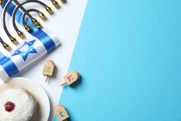 Flat lay composition with golden menorah, Israel flag, sufganiyot and dreidel set. Happy Hanukkah greeting card with Jewish decor on blue background 
