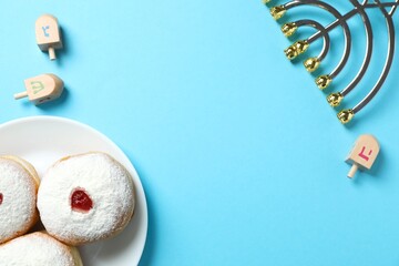 Hanukkah stylish presentation. Top view of traditional Jewish meal - sufganiyot, menorah and dreidel set on blue backdrop 