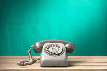 Vintage old telephone on wood table with turquoise wall background