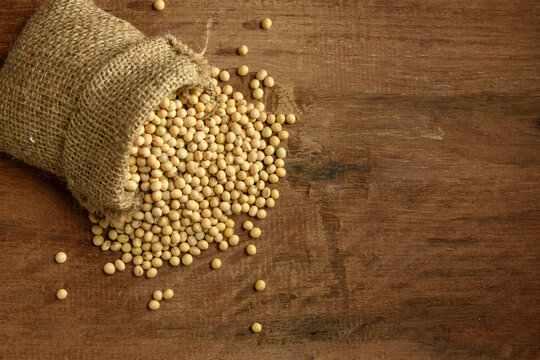 Soy beans in sack on wooden board
