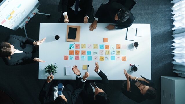 Top down ariel view of professional project manager present idea while putting together and clapping hand to celebrate successful strategy at meeting room. Show unity, love, teamwork. Directorate.