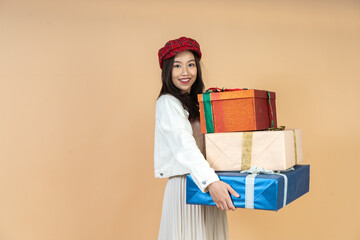 Young Asian Woman with Stack of Holiday Gifts Expressing Surprise and Joy During Christmas Season Shopping Experience in Studio Perfect for Seasonal Marketing