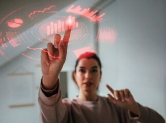 Young woman analyzing digital data charts using futuristic interface