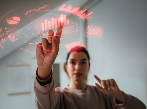 Young woman analyzing digital data charts using futuristic interface