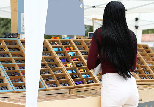 Mujer de compras en puesto de mercadillo con expositor de gafas de sol