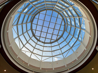 A round glass decorative ceiling with a modern design against a blue sky background.