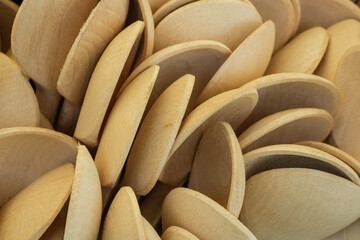 Wooden spoons stacked closely together showing various shapes and angles in a bright, natural light setting