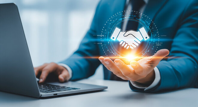 Man in suit using laptop with handshake hologram above hand suggesting business partnership online deal - Powered by Adobe