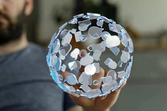 A person holds a futuristic digital sphere with speech bubble icons. Concept of communication, social media, connection, and data exc