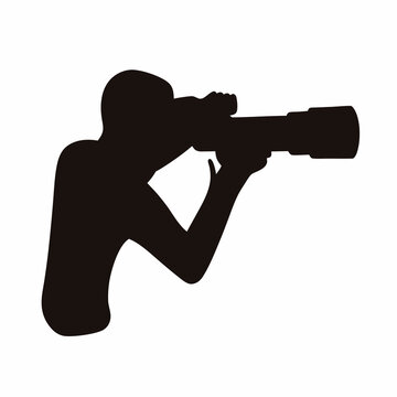 Fototapeta Silhouette of a person looking through a large camera lens precisely