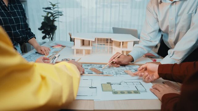 A dynamic office scene showcasing diverse professionals actively collaborating on architectural plans and models, highlighting teamwork and creativity in design projects. SACTR