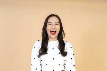 Close up headshot of a beautiful young and happy asian woman smiling cheerfully and showing authentic joy in a bright studio