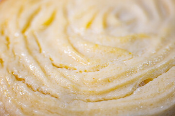 Detailed view of golden puff pastry rolls with a spiral pattern and glossy finish, placed on a white background. Lightly browned edges and soft, layered texture are visible.
