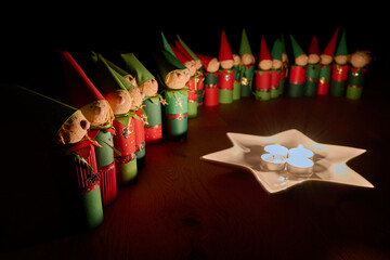 Wichtelfiguren aus Papier als Adventskalender vor einem Sternenteller mit vier Kerzen