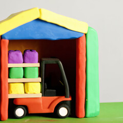 Mini clay shipping center with colorful forklift carrying purple, green, and yellow packages inside vibrant warehouse