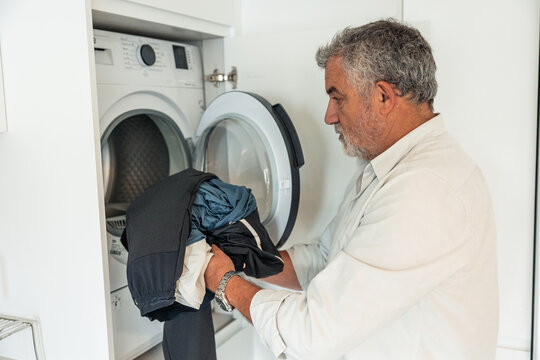 Senior man doing laundry at home daily routine