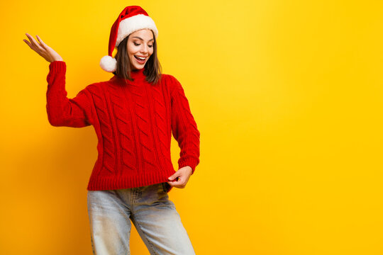 Playful santa moment with a red knit sweater girl posing in bright yellow backdrop holiday vibe fun festive mood