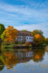 Obraz premium Schloss Muskau, Muskau palace, Saxony, Germany. UNESCO World Heritage Site. Autumnal landscape at the Prince Pückler Park, Bad Muskau. Palace on the lake. Reflection in water