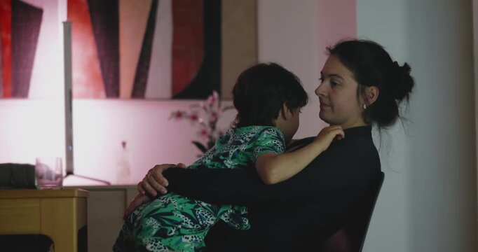 Mother holding child in warm intimate moment as they lean close and share quiet affection in relaxed home environment with gentle emotional connection