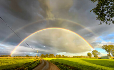 A breathtaking view of a stunning double rainbow gracefully arching over vibrant green fields...
