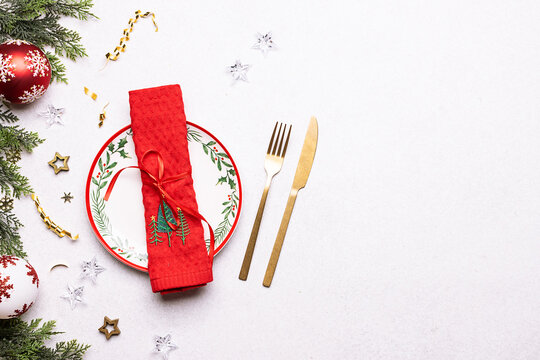 Bright plates, napkin and cutlery set on white stone background with copy space for your design top view. Festive Christmas table setting.
