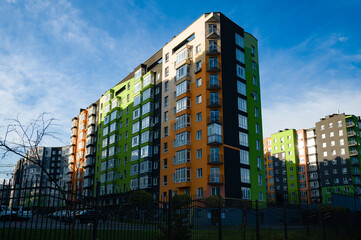 Vibrant modern apartments stand tall against a clear blue sky in a bustling neighborhood filled...