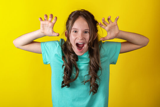 Angry young caucasian teen girl holding hands up against yellow background