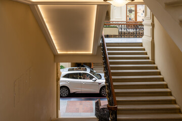 Fototapeta premium Historic interior shopping centre with marble staircase and modern car creating urban contrast