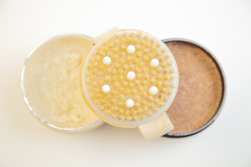 Round exfoliating body brush with textured bristles, placed alongside natural skincare products, showcasing beauty essentials for effective self-care and skin health
