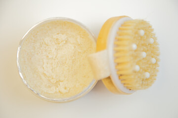 Exfoliating scrub displayed in a round container with a wooden brush lid, highlighting creamy texture and inviting aroma, perfect for skincare routines and self-care moments