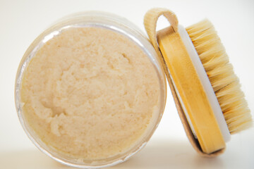 Body scrub displayed in a glass jar alongside a wooden brush, highlighting its creamy texture and inviting look for skincare and beauty routines