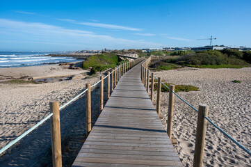 Obraz premium Boardwalk over dunes of Canide Beach on northern coast of Portugal in Vila Nova de Gaia under dramatic autumn cloudscape.