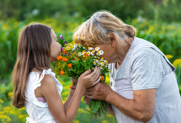 Grandmother and granddaughter hold medicinal herbs and flowers in their hands. Selective focus.