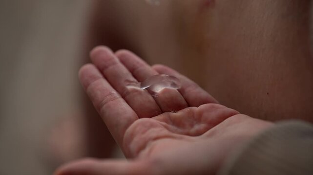 Close up of female hands applying transparent healing gel to large bruise and hematoma on leg, gently massaging ointment into injured skin for first aid treatment. Concept of trauma, medical attention