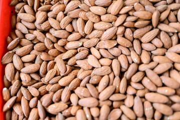 Almonds filling a red container at market