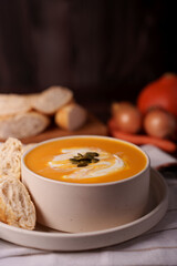 warm and inviting autumn soup with creamy texture and pumpkin seeds, paired with fresh baguette slices, set against a rustic table with onions and bread in the background, dish, entrée, snack