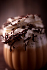 close-up view of luxurious whipped cream with chocolate sprinkles on a steaming hot beverage in a cozy, dimly lit setting emphasizing rich textures and comforting warmth, bubbly, smooth, satisfying