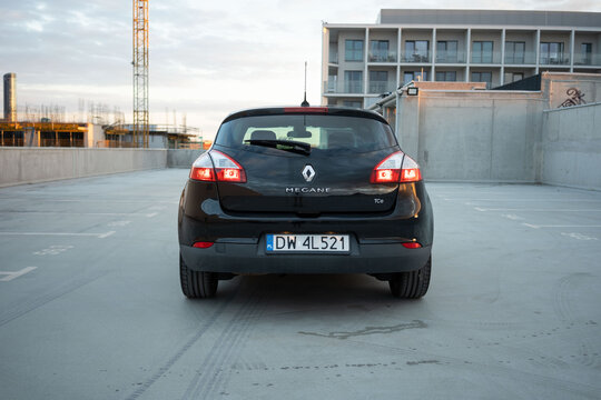 Wroclaw, Poland - August 18, 2025: Rear view of a black Renault Megane TCe hatchback parked on a rooftop at sunset, showcasing its taillights, branding, and compact urban design.