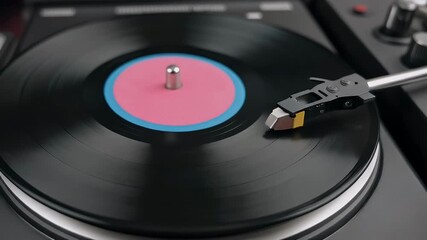 A close-up view of a vintage turntable playing a black vinyl record with a vibrant pink and blue label. - Powered by Adobe