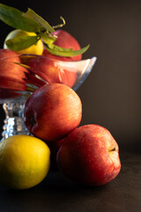Still Life with Red Apples and Lemons in a Glass Vase on Black Background