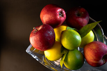 Still Life with Red Apples and Lemons in a Glass Vase on Black Background
